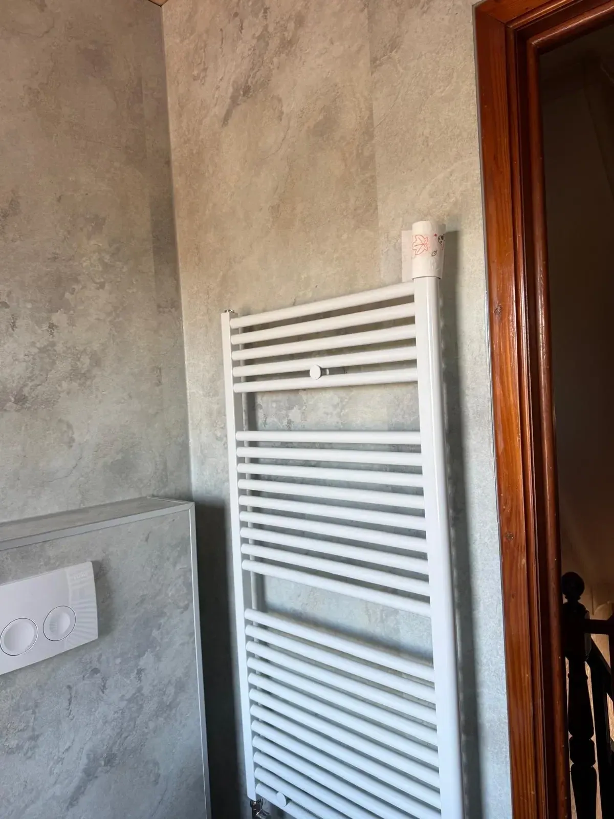 Grijze betonlook wandpanelen met witte handdoekradiator en bedieningsplaat van hangtoilet