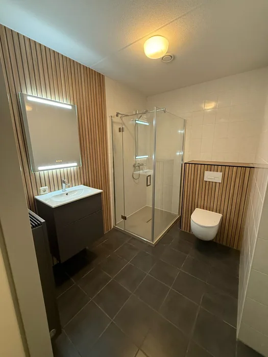 Houtlook & lamellen: Complete badkamer met houten lamellen, led-spiegel, douchecabine, hangtoilet en donkere vloer