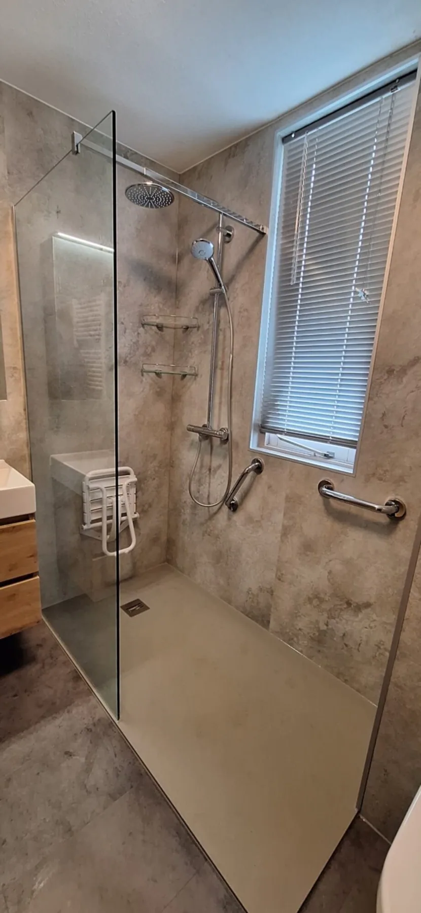 Inloopdouche met beige marmerlook wandpanelen, regendouche, glazen wand, steunbeugel en douchezitje