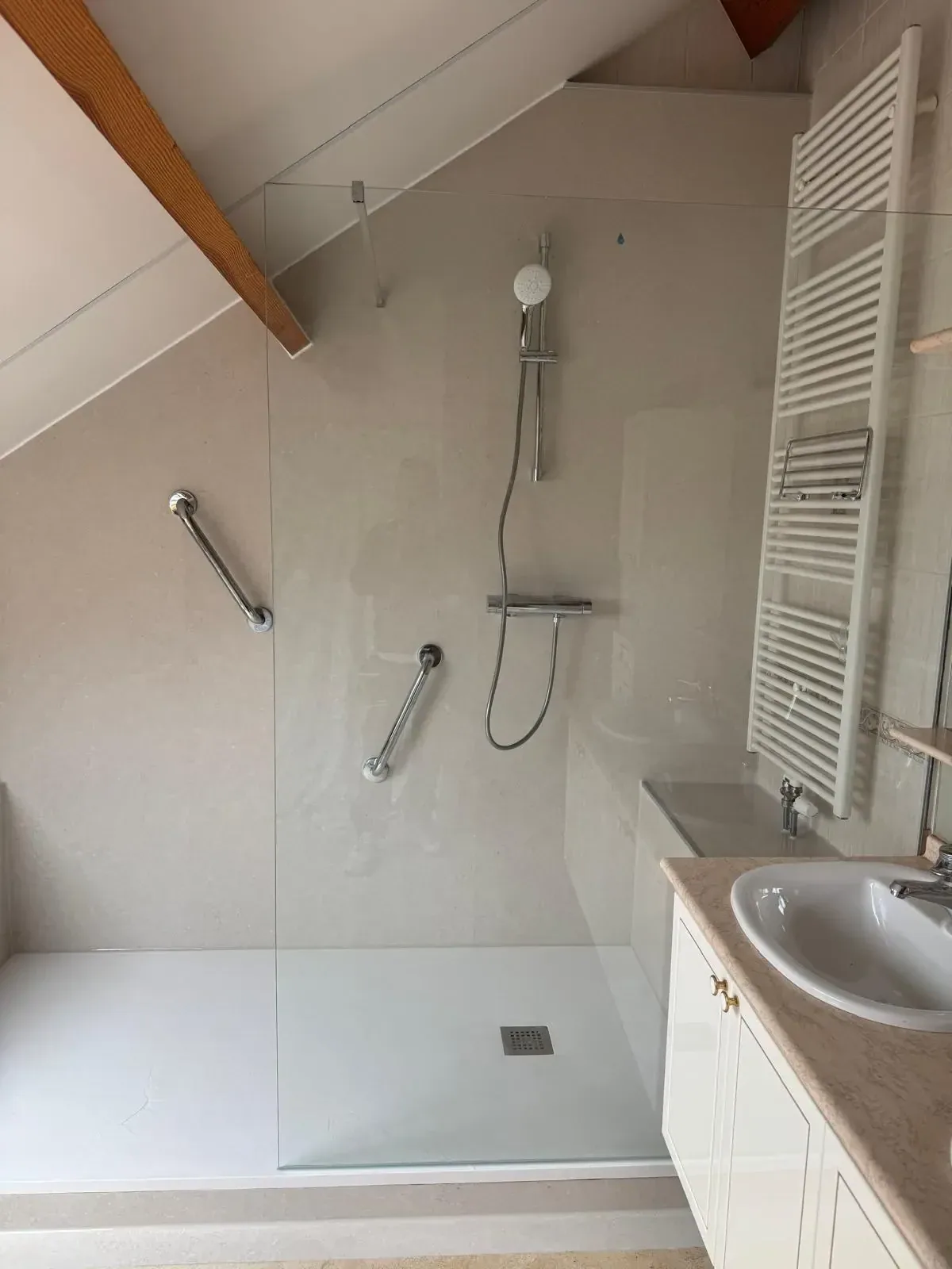 Inloopdouche onder schuin dak met glazen wand, thermostaatkraan, twee steunbeugels en witte handdoekradiator