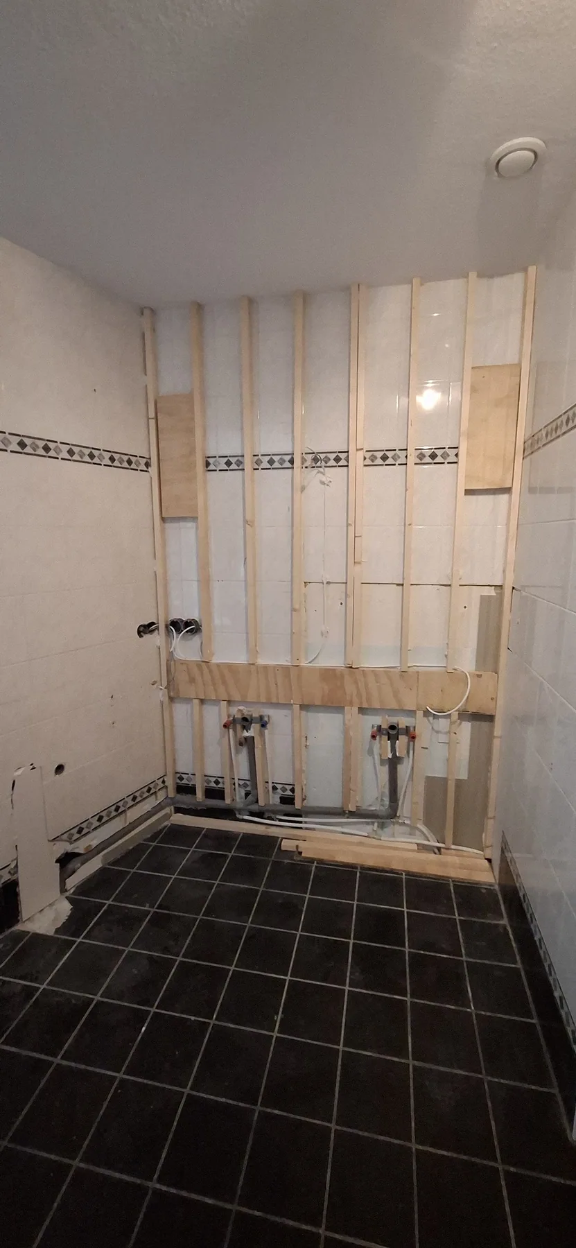 Regelwerk op de badkamerwand voor wandpanelen, nieuwe waterleidingen onderaan