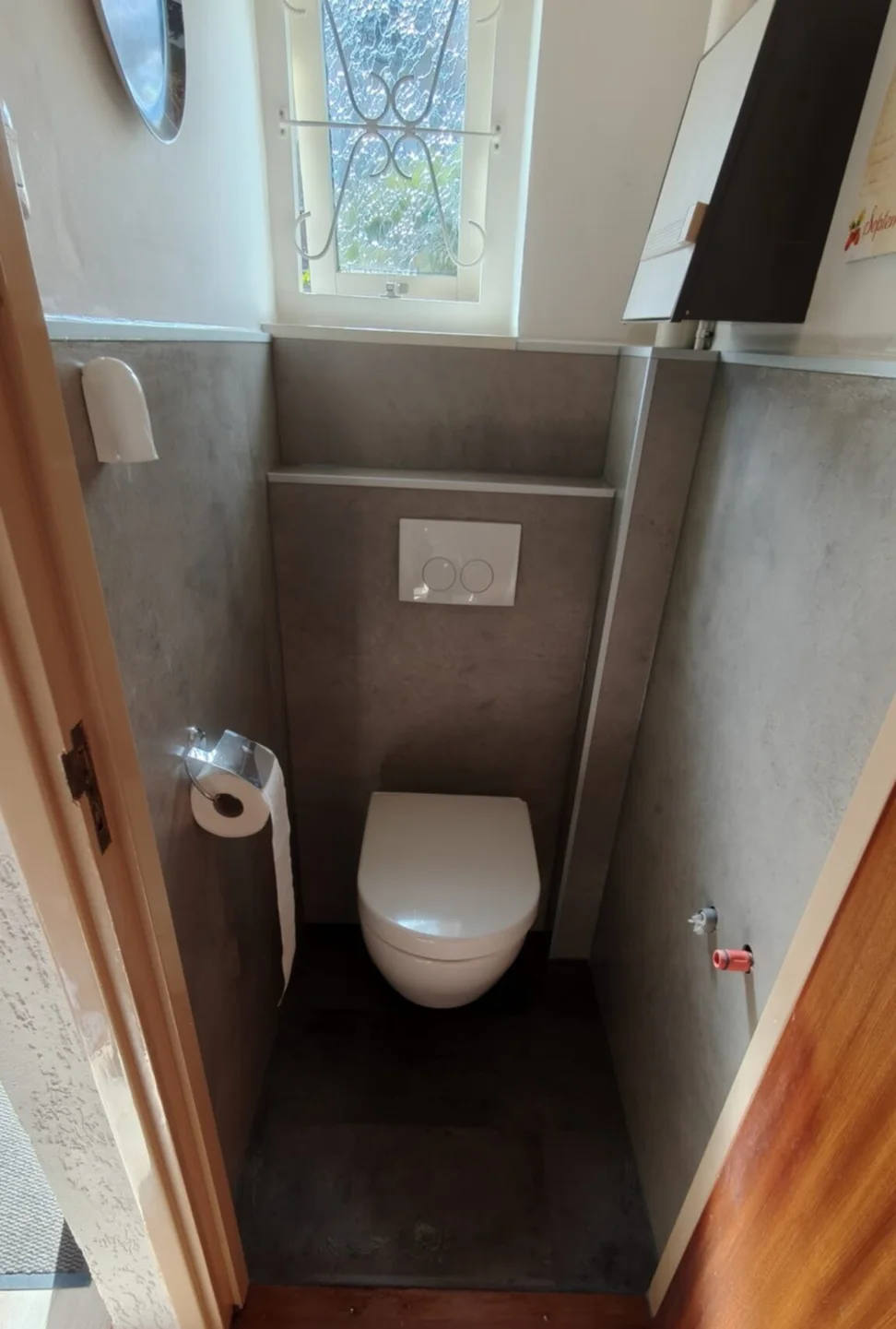 Na: hangtoilet tegen een voorzetwand met wandpanelen en donkere vloer